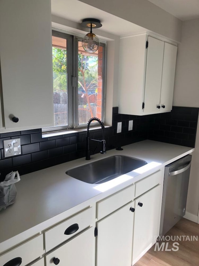 3109 N Tamarack Dr, Boise, ID 83703 - kitchen featuring stainless steel dishwasher, white cabinetry, light countertops, a sink, and backsplash