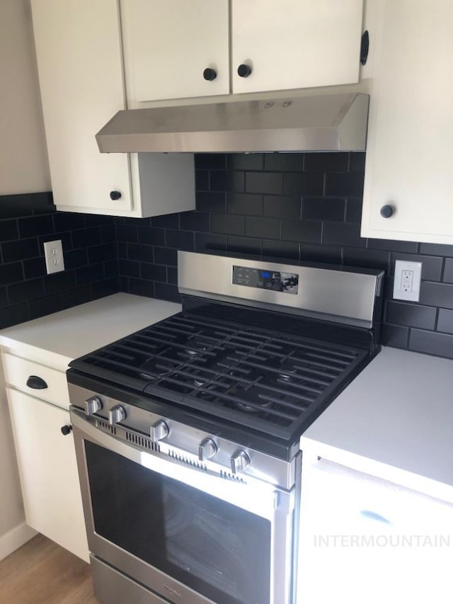 3109 N Tamarack Dr, Boise, ID 83703 - kitchen with light countertops, stainless steel range with gas cooktop, under cabinet range hood, white cabinetry, and decorative backsplash