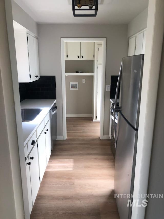 3109 N Tamarack Dr, Boise, ID 83703 - kitchen with white cabinetry, appliances with stainless steel finishes, a sink, light wood finished floors, and backsplash