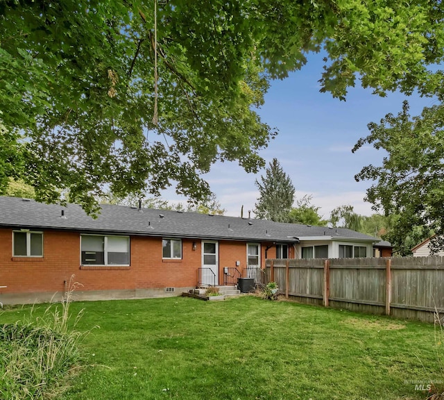 3109 N Tamarack Dr, Boise, ID 83703 - rear view of house featuring brick siding, fence, central AC, and a lawn