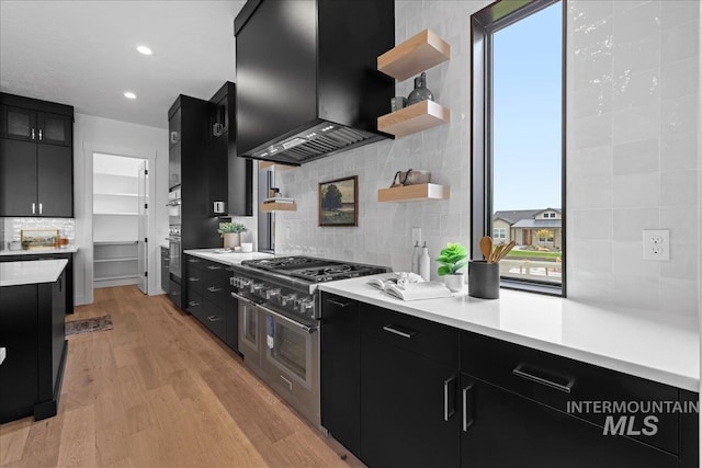 13625 Hickory Rnch, Nampa, ID 83651 - kitchen with dark cabinetry, extractor fan, decorative backsplash, light wood-style floors, and light countertops