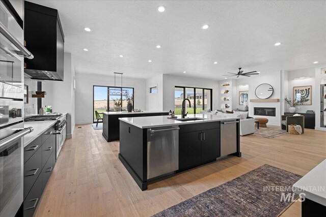 13625 Hickory Rnch, Nampa, ID 83651 - kitchen featuring dark cabinetry, an island with sink, stainless steel dishwasher, recessed lighting, and a sink