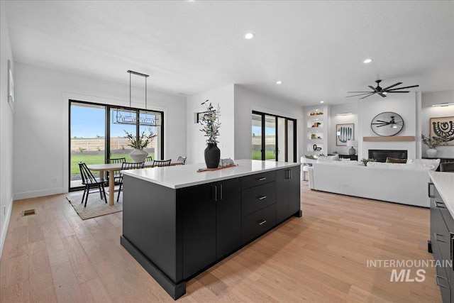 13625 Hickory Rnch, Nampa, ID 83651 - kitchen with dark cabinets, light countertops, a kitchen island, light wood-style floors, and recessed lighting