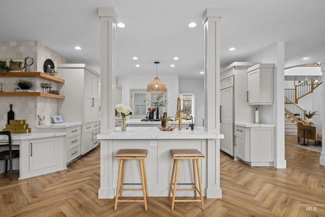 3031 Champagne Ct, Eagle, ID 83616 - kitchen with a breakfast bar area, a center island, decorative columns, backsplash, and paneled refrigerator