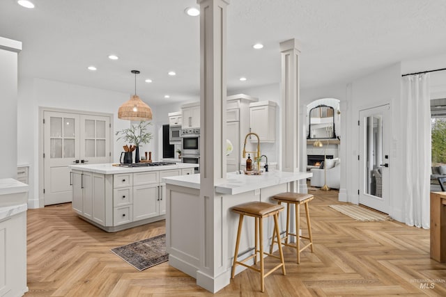 3031 Champagne Ct, Eagle, ID 83616 - kitchen featuring gas cooktop, double oven, decorative columns, and an island with sink