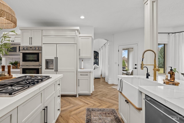 3031 Champagne Ct, Eagle, ID 83616 - kitchen featuring a sink, stainless steel appliances, white cabinets, arched walkways, and recessed lighting