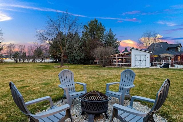 3031 Champagne Ct, Eagle, ID 83616 - yard at dusk featuring a fire pit, an outbuilding, fence, and a storage unit