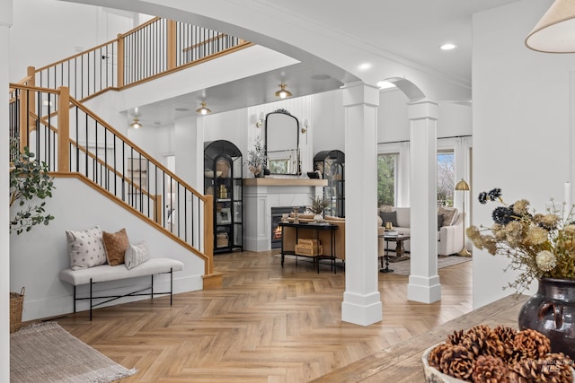 3031 Champagne Ct, Eagle, ID 83616 - entryway featuring ornate columns, a lit fireplace, stairway, arched walkways, and recessed lighting