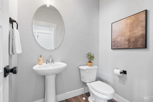 bathroom featuring toilet, wood finished floors, a sink, and baseboards