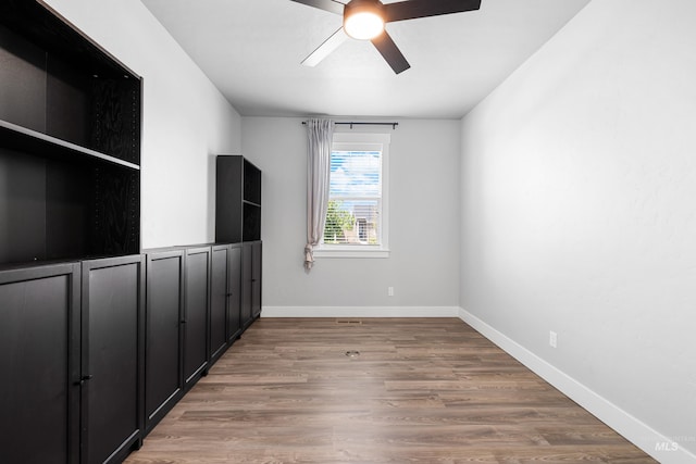 empty room featuring a ceiling fan, light wood-type flooring, and baseboards