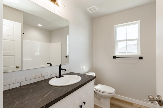 bathroom with hardwood / wood-style floors, toilet, a shower, and vanity