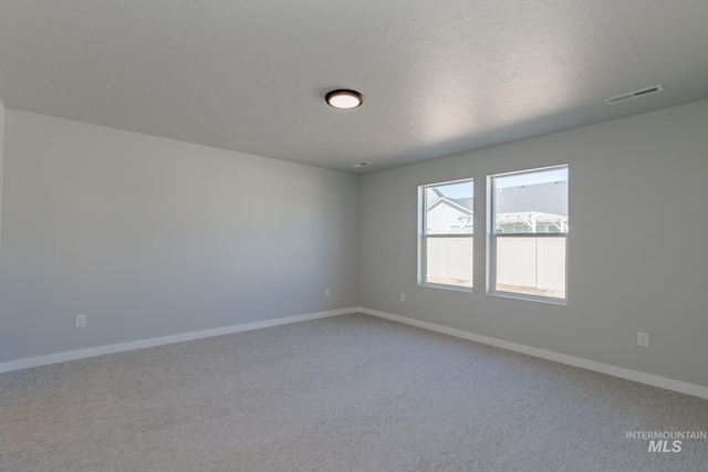 carpeted empty room featuring a textured ceiling