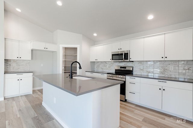 kitchen featuring white cabinets, a center island with sink, appliances with stainless steel finishes, and sink