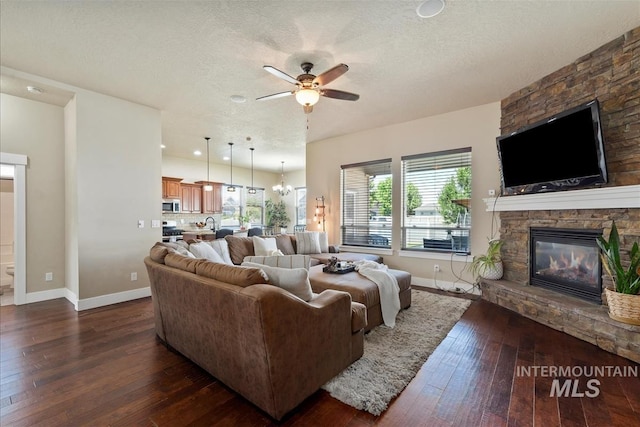 730 N Finsbury Way, Star, ID 83669 - living area with dark wood-style flooring, a stone fireplace, a ceiling fan, and a textured ceiling