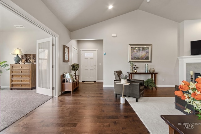entrance foyer with visible vents, a glass covered fireplace, wood finished floors, baseboards, and vaulted ceiling