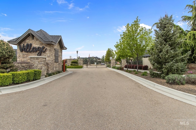 view of road with a gate, a gated entry, and curbs