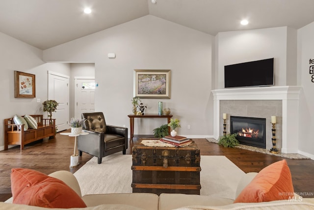 living room featuring wood finished floors, a tile fireplace, baseboards, lofted ceiling, and recessed lighting