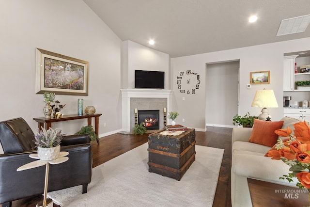 living area with visible vents, lofted ceiling, wood finished floors, a fireplace, and baseboards