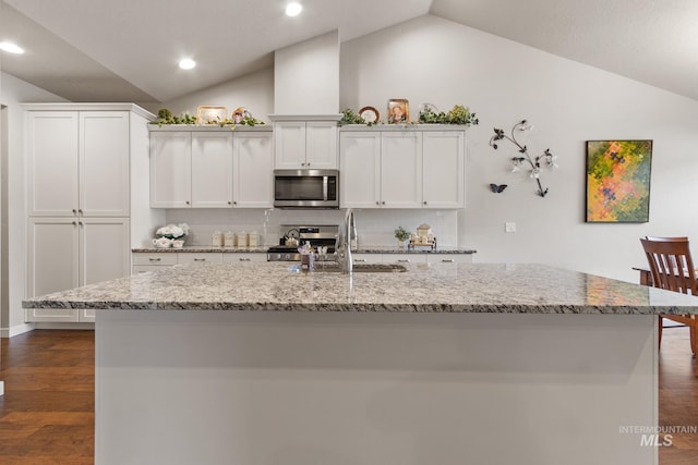 kitchen with a kitchen island with sink, dark wood finished floors, appliances with stainless steel finishes, and lofted ceiling