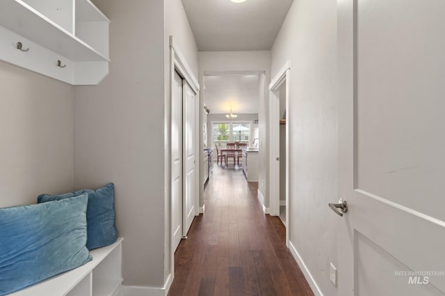 hallway featuring baseboards and dark wood finished floors