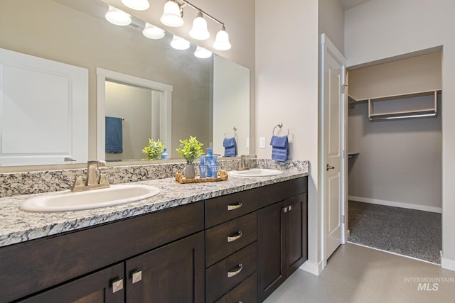 full bath featuring a sink, baseboards, and double vanity