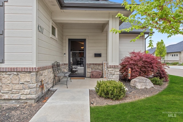 view of exterior entry featuring a porch and stone siding