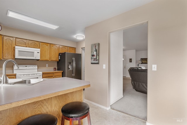 386 E Valleyview Ave, Genesee, ID 83832 - kitchen with white appliances, a sink, a breakfast bar, light countertops, and a peninsula