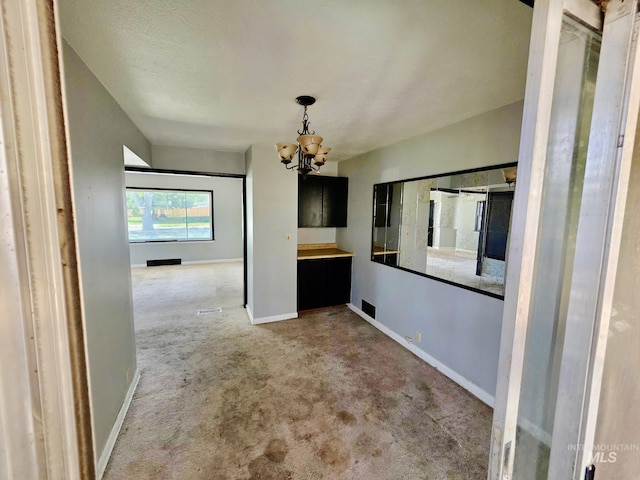 unfurnished dining area with carpet flooring, a chandelier, and baseboards