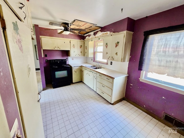 kitchen with electric range, a sink, light countertops, and cream cabinetry