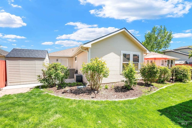 1177 N Lopez Ave, Eagle, ID 83616 - back of house with a storage shed, an outdoor structure, a lawn, roof with shingles, and central AC