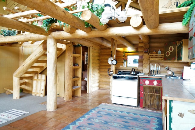 kitchen with log walls, white range with gas cooktop, light tile floors, sink, and tile countertops