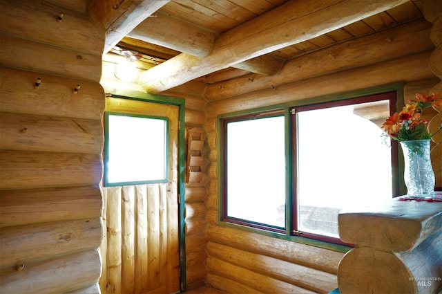 interior space featuring a wealth of natural light, log walls, and beamed ceiling