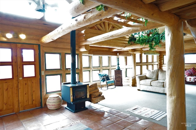 interior space featuring beamed ceiling, wood ceiling, a wood stove, and wooden walls