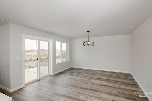 unfurnished dining area featuring light hardwood / wood-style flooring and a chandelier