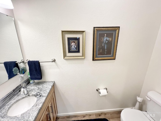 bathroom with toilet, vanity, and baseboards