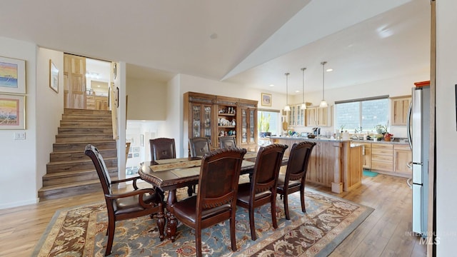 dining area with light wood finished floors, recessed lighting, vaulted ceiling, and stairway