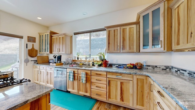 kitchen with glass insert cabinets, light wood-style flooring, light stone counters, and dishwasher