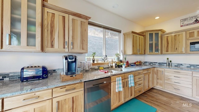 kitchen featuring light wood-type flooring, light stone counters, light brown cabinetry, and dishwashing machine