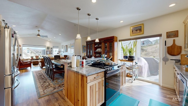 kitchen featuring open floor plan, freestanding refrigerator, light wood finished floors, gas stove, and light stone counters