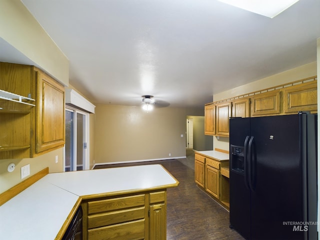 kitchen featuring black fridge with ice dispenser, built in desk, kitchen peninsula, and dark wood-type flooring