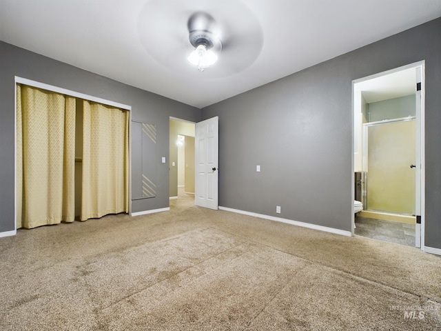 unfurnished bedroom featuring a closet, ensuite bathroom, ceiling fan, and carpet flooring