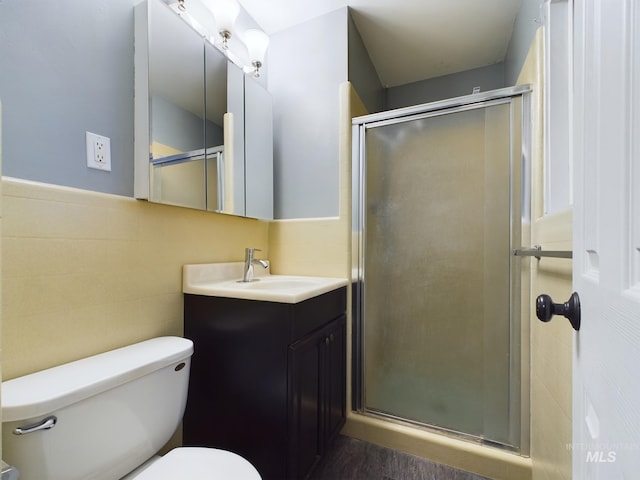 bathroom featuring tile walls, vanity, a shower with door, and toilet