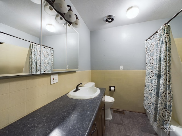 full bathroom featuring tile walls, shower / tub combo, vanity, a textured ceiling, and toilet