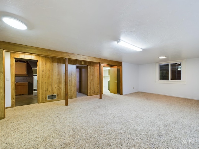 basement featuring carpet flooring and wood walls