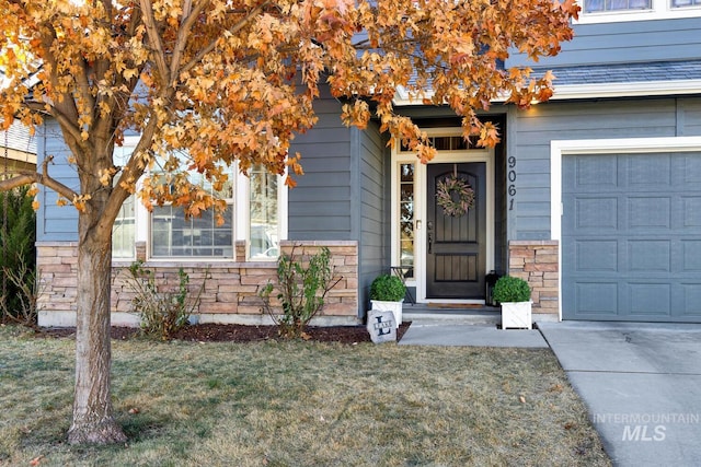 doorway to property with a garage and a lawn