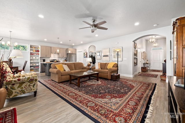 living room with ceiling fan with notable chandelier, sink, a textured ceiling, and hardwood / wood-style floors