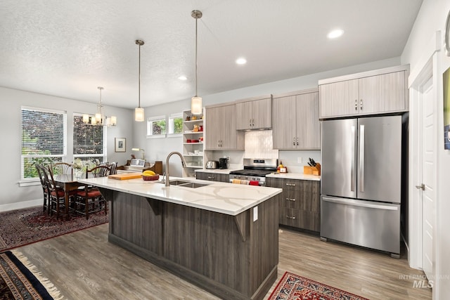 kitchen featuring stainless steel appliances, a kitchen island with sink, wood-type flooring, and sink