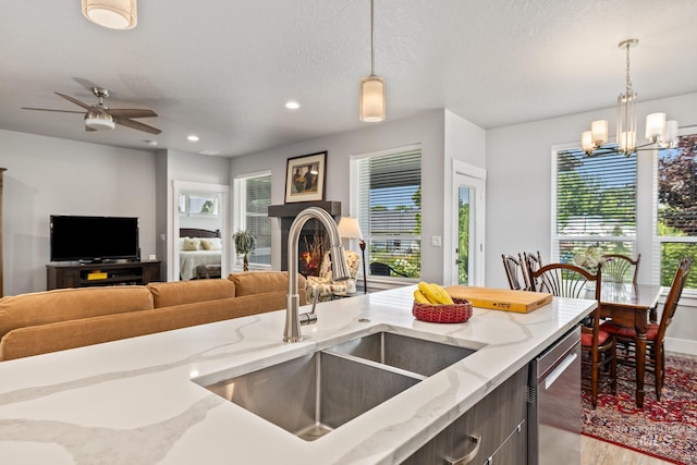 kitchen featuring light stone countertops, a healthy amount of sunlight, hanging light fixtures, and sink