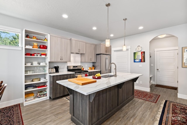 kitchen with stainless steel appliances, sink, a kitchen island with sink, wood-type flooring, and a breakfast bar