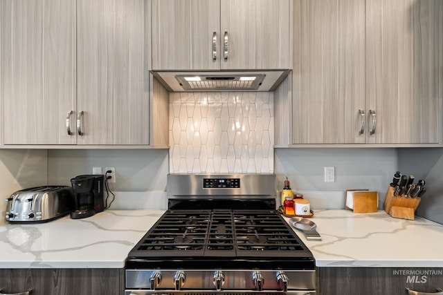 kitchen with stainless steel gas range, extractor fan, and light brown cabinets